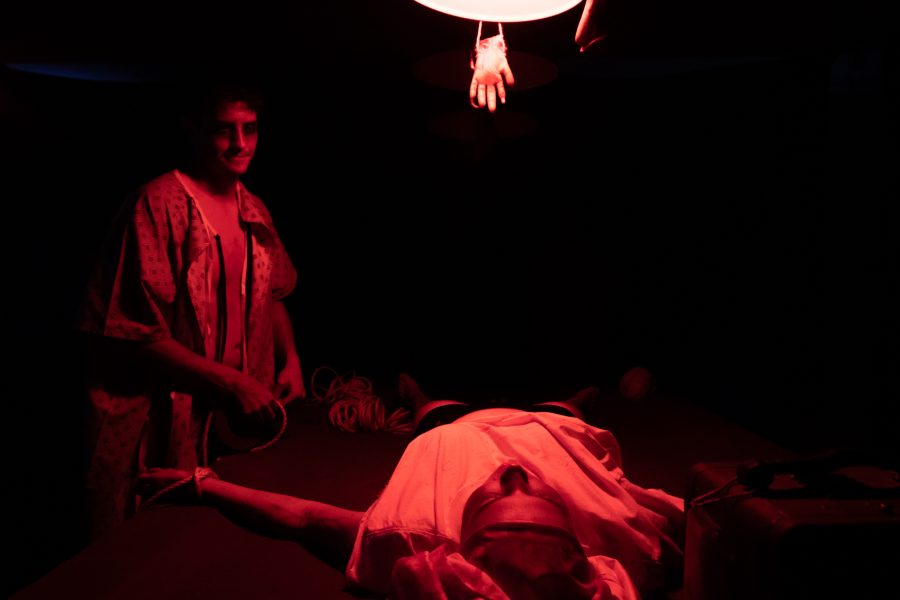 Ryne Johnson straps Kristie Davis to the table for a “SAW” themed room at the Theta Chi fraternity haunted house Oct. 22. (Grayson Reed | The Collegian)