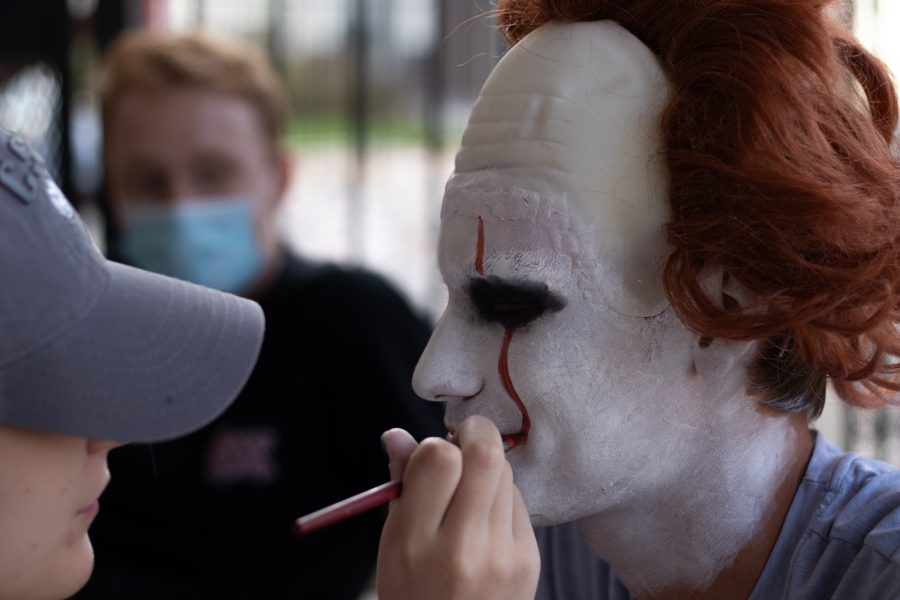 Michael Brust gets his makeup done by Ella White to play as Pennywise from the movie “It” at the Theta Chi fraternity haunted house Oct. 22. (Grayson Reed | The Collegian)