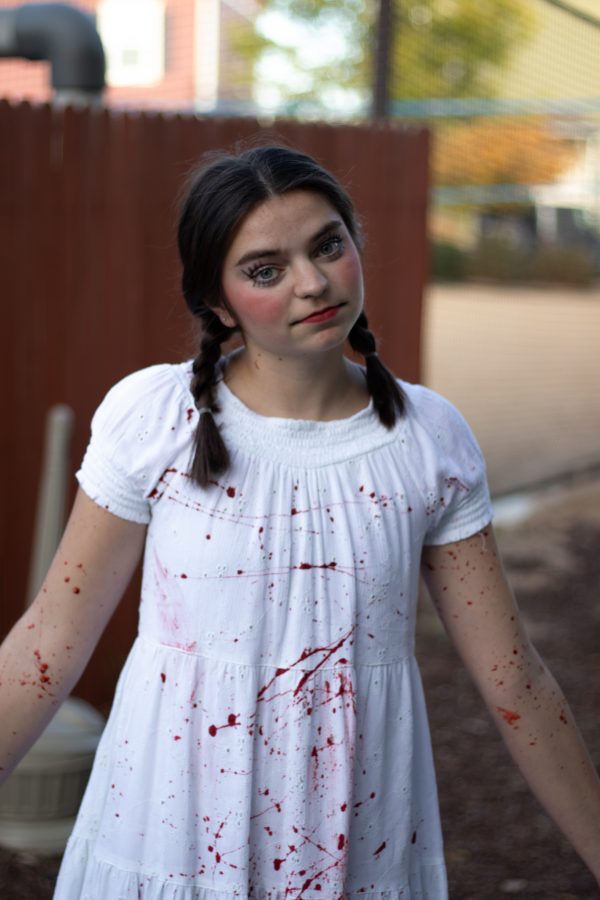 Katie Nieuwlandt gets blood thrown at her scary doll costume before the Theta Chi fraternity haunted house Oct. 22. (Grayson Reed | The Collegian)