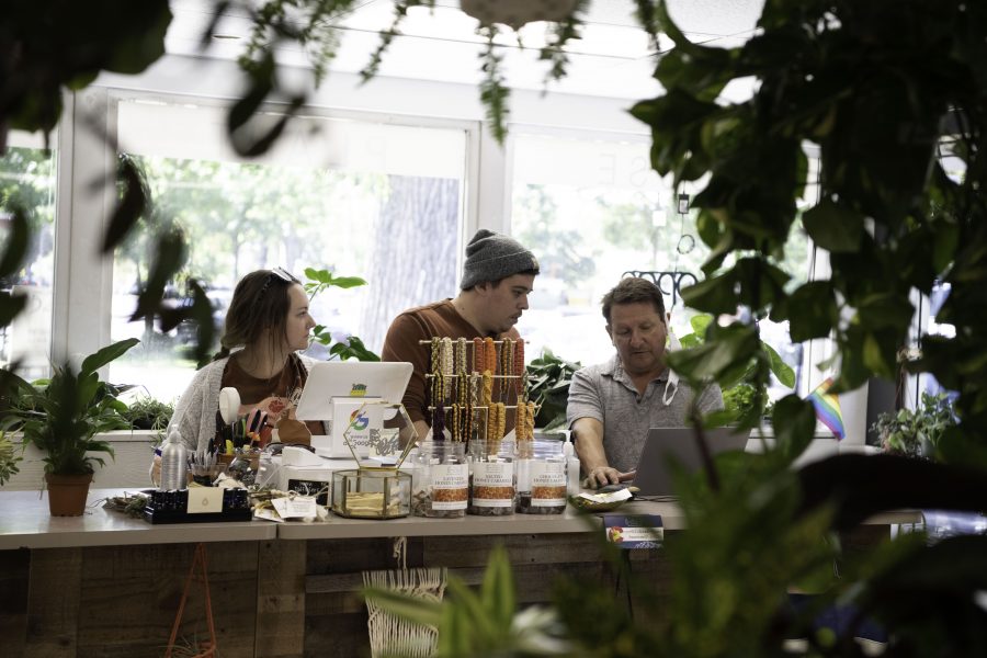 Kaley Halligan (Left) Korey Halligan (Middle) and David Cantor (Right) co-owners of Horsetooth Stems and Roots House Plant Boutique in Fort Collins Colorado stand behind the counter looking at a laptop Oct. 4. (Garrett Mogel | The Collegian)