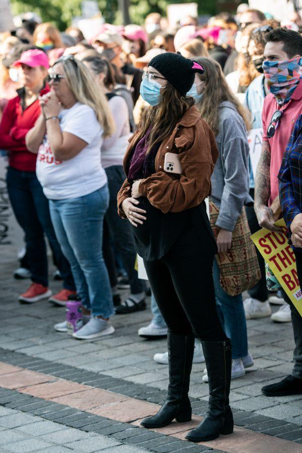 A Women’s March-goer watches speakers at the Colorado State Capitol while holding and rubbing their stomach Oct. 2. (Lucy Morantz | The Collegian)