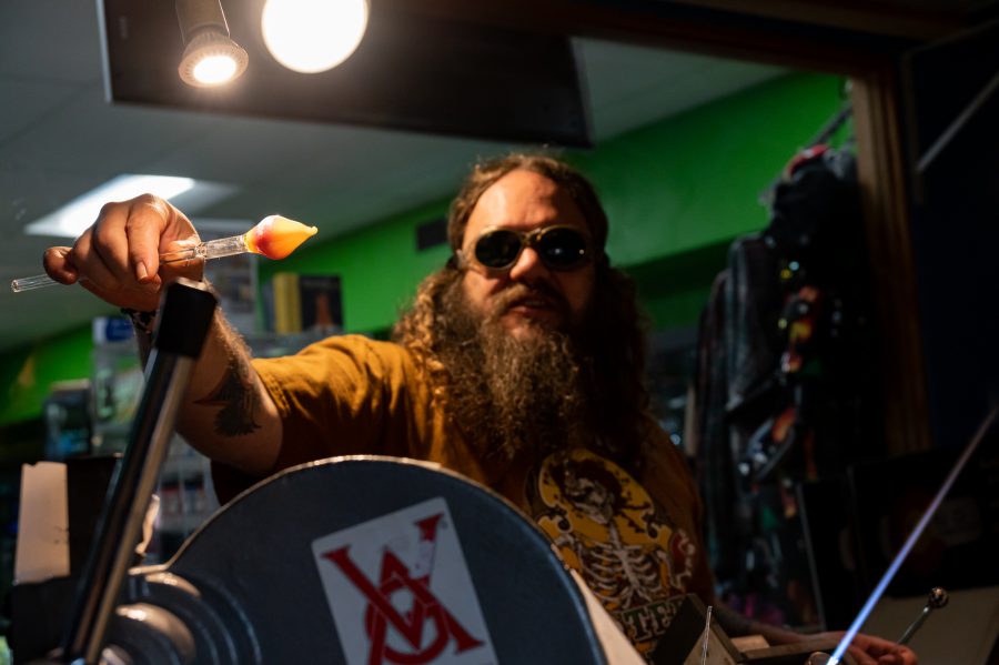 Skye Norton shows one of his newest projects in Kind Creations Nov. 9. Norton explained that some colors are very delicate and can change from purple to blue just through more exposure to heat. (Milo Gladstein | The Collegian)