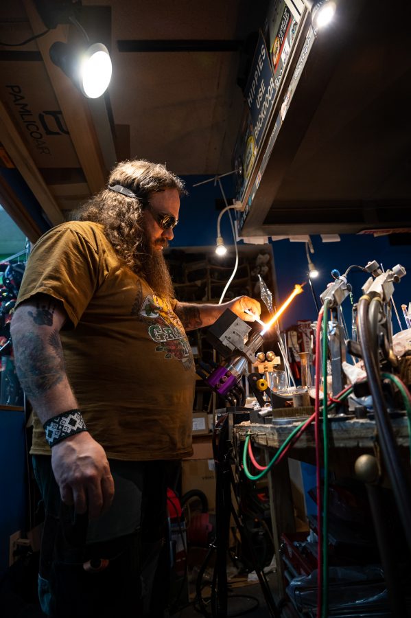 Skye Norton heats up a piece of glass at Kind Creations Nov. 9. Norton stated, “This technique is called a wig wag so it’s an older take on an older technique.” This involves getting a small flame and adding what are known as kickbacks. (Milo Gladstein | The Collegian)