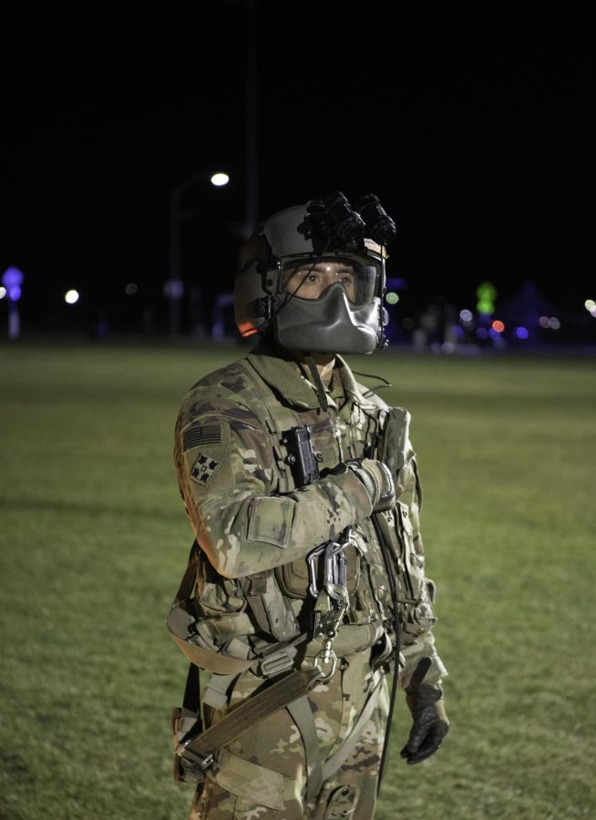 Specialist Brian Torres of the 4th Combat Aviation Brigade talks to a UH-60L Black Hawk from the 4th Combat Aviation Brigade before take-off from the Colorado State University Intermural Fields Nov. 13. The mask Torres is wearing serves two purposes, one being a shield from wind, as well as a cover for the microphone he uses to communicate with the pilots. The helicopter was requisitioned by the CSU Army ROTC to make an appearance for military appreciation day as well as CSUs football game against Air Force which resulted in a win for Air Force (35-21). (Garrett Mogel | The Collegian)