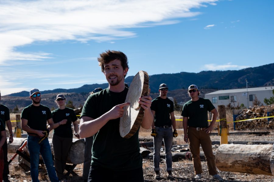 Henry Talor holds a cut piece of wood known as a cookie while explaining the rules and technique of the stock saw event Nov. 14. (Milo Gladstein | The Collegian)
