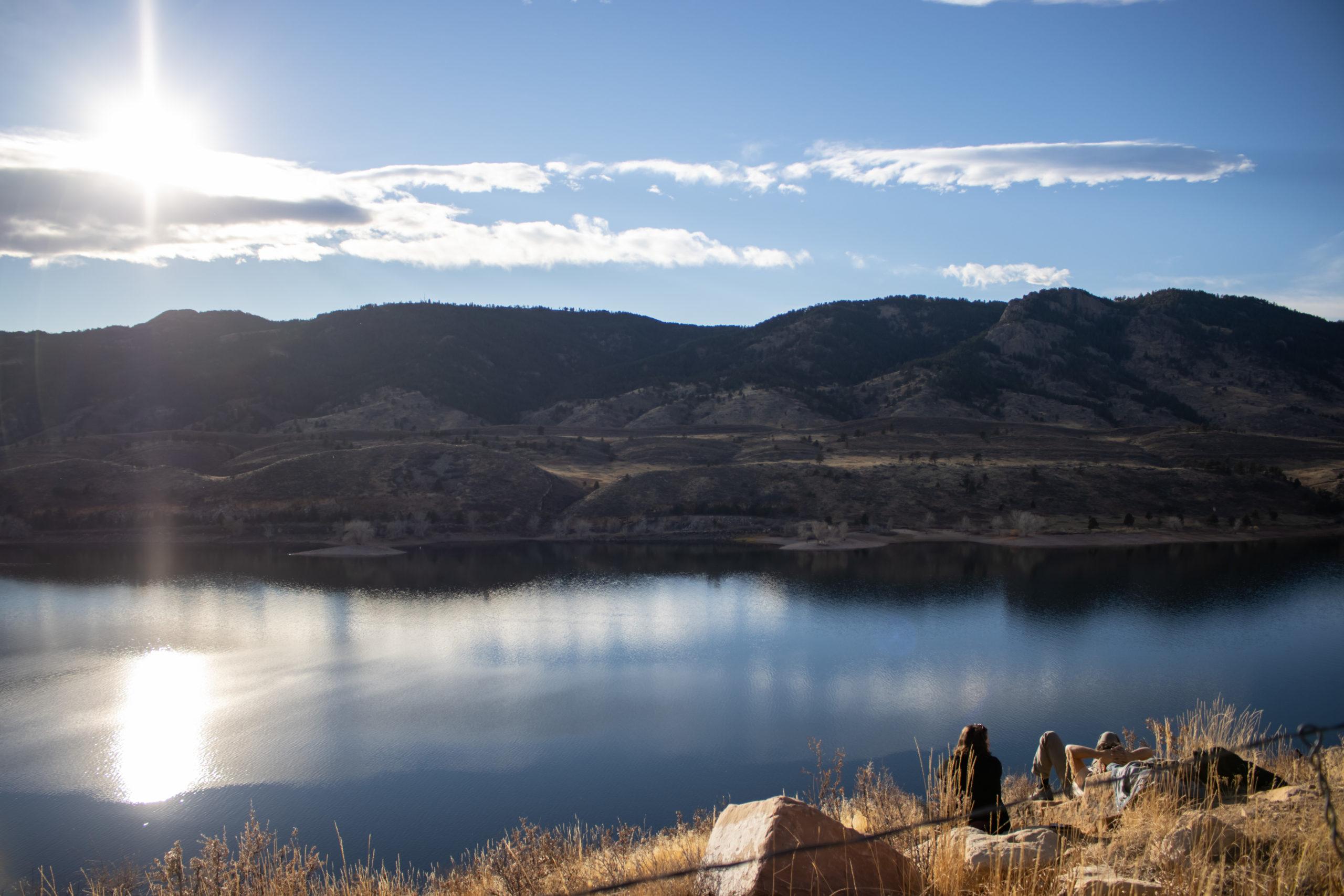 Two people sit looking out over Horsetooth Reservoir.