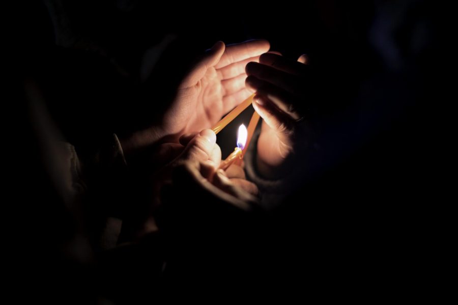 Three people light candles from one another during the third night of Hanukah Nov. 30.