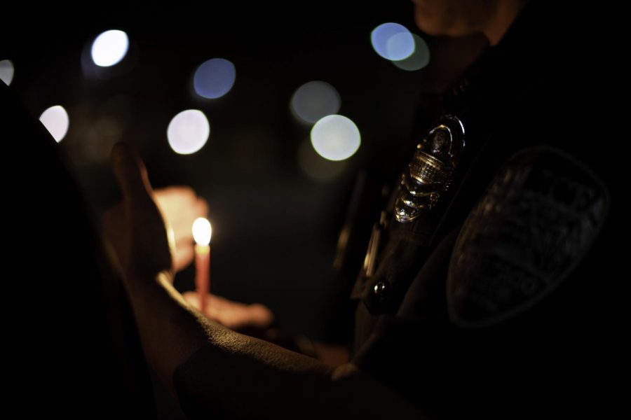 A Colorado State University police office lights a candle during the third night of Hanukah Nov. 30. The celebration took place on the CSU Lory Student Center Plaza featuing guest speakers, Jewish sororities, fraternities and president Joyce McConnell. (Garrett Mogel | The Collegian)  