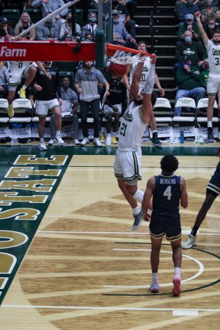 Colorado State University forward David Roddy (21) dunks the ball while a defender looks on. Photographer: Avery Coates