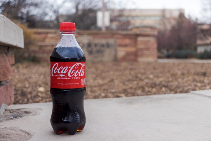 A bottle of Coca-Cola in front of a Colorado State University sign