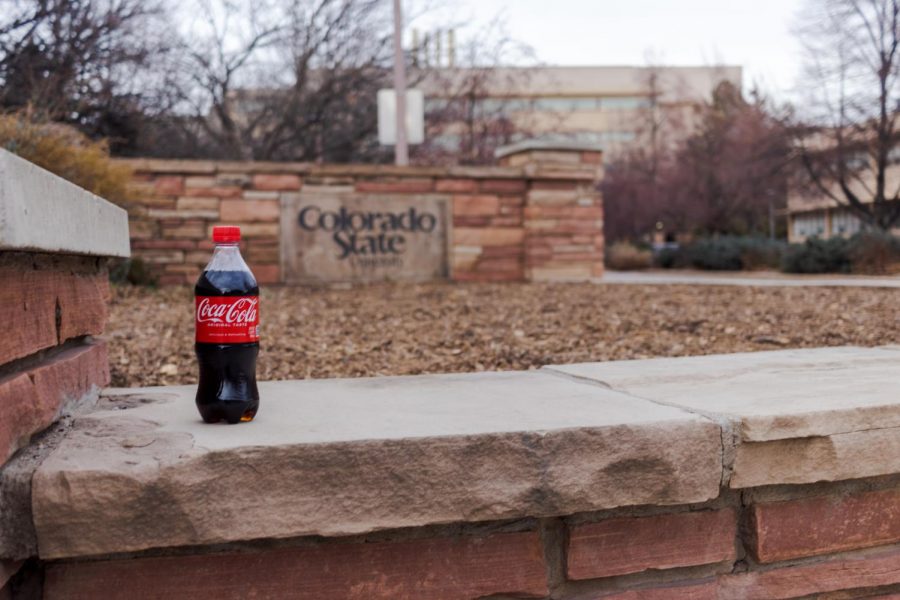 A bottle of Coca-Cola in front of a Colorado State University sign