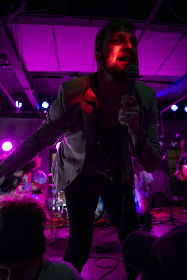 Kyle Morris, Lead Singer of the Unlikely Candidates crouches down to crowd level while singing one of the band's songs at The Coast in Fort Collins Colorado Jan. 19. 22