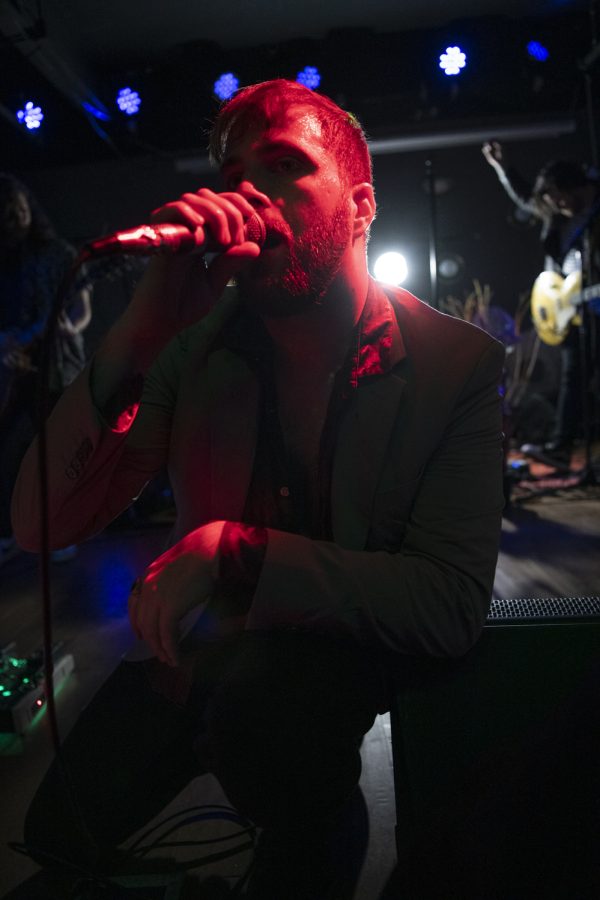 Kyle Morris, Lead Singer of the Unlikely Candidates crouches down to crowd level while singing one of the band's songs at The Coast in Fort Collins Colorado Jan. 19. 22