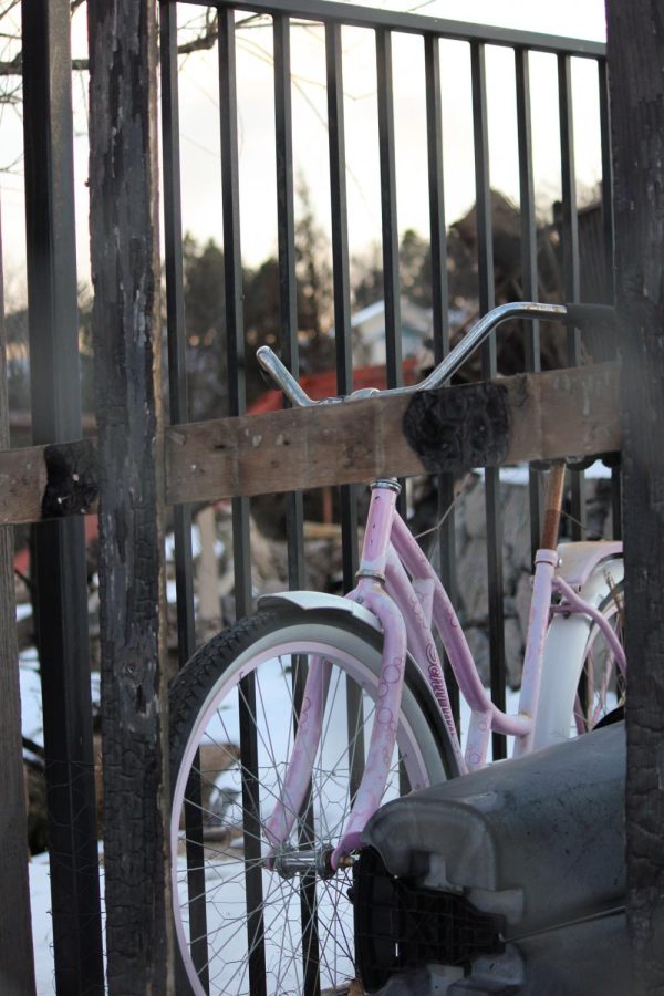 A young girl’s bike leans against a charred fence.