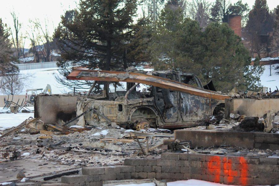 What looks to be a Jeep wrangler sits burnt with a fallen beam on top.