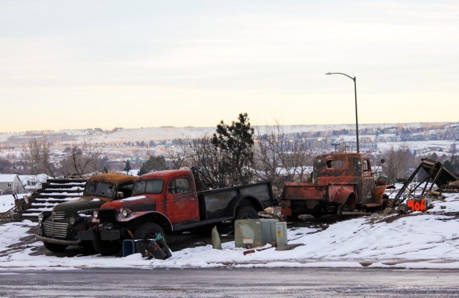 A group of classic Chevrolet trucks sit among the rubble.