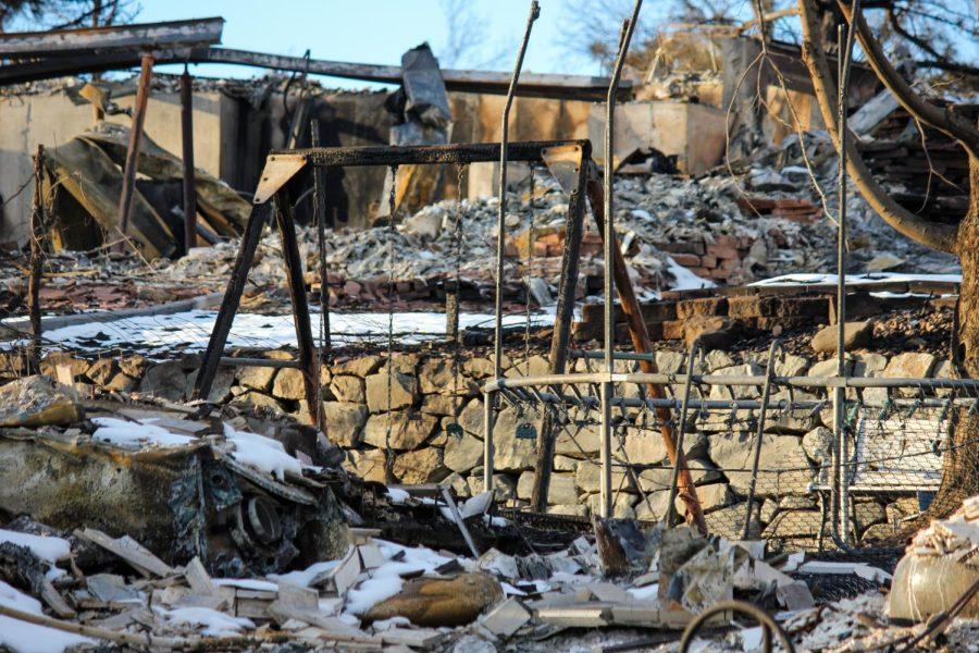 The frames of a swing set and trampoline remain standing among the rubble.