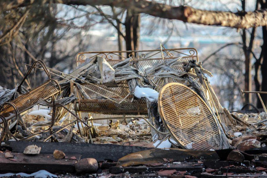 A patio table and chair set remain intact with burn marks and fallen debris on top.