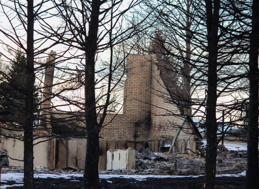 The brick wall of a house stands alone, charred from the fire.