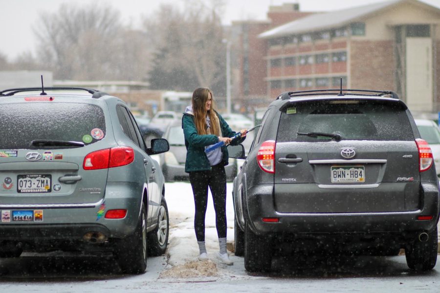 A CSU student scrapes the ice from her car.
