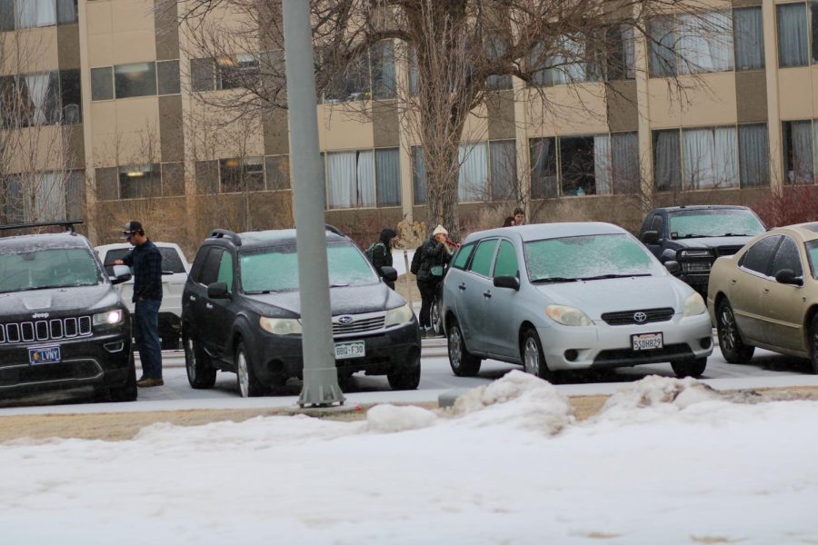 Students attempt to scrape ice off of their car windows.