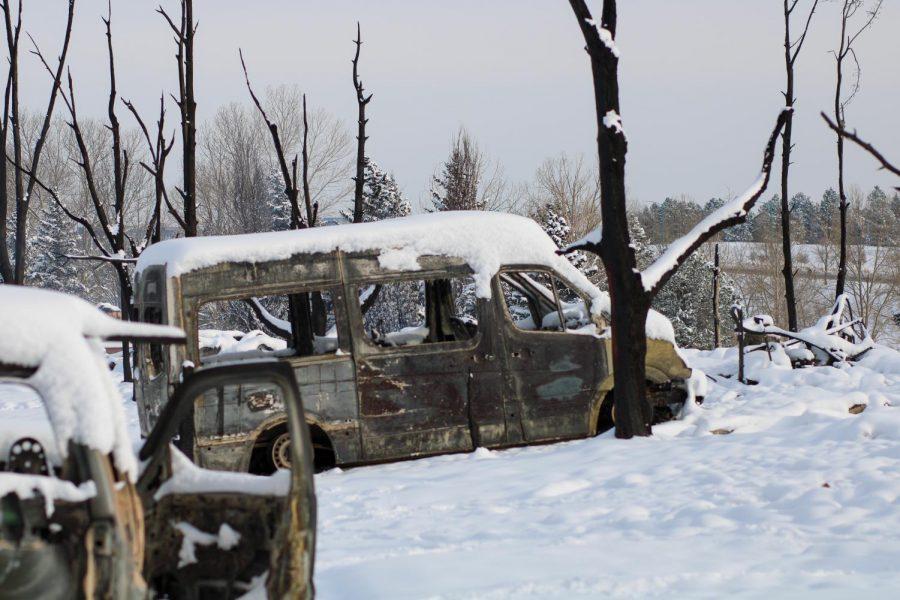 A charred sprinter van sits parked in what used to be a driveway.