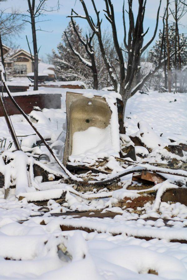 A burnt bathtub sits uprooted amognst the remains of what used to be a house.