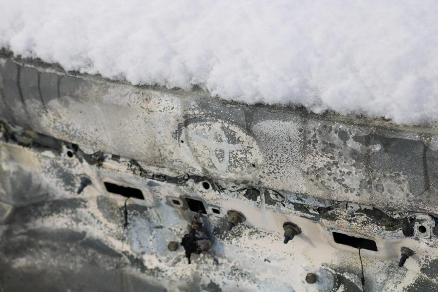The outline of a Toyota emblem remains on the bumper of a charred car.
