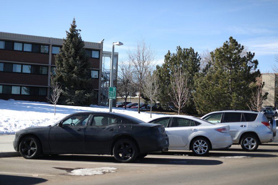 Three cars are diagonally parked along a street on a sunny day