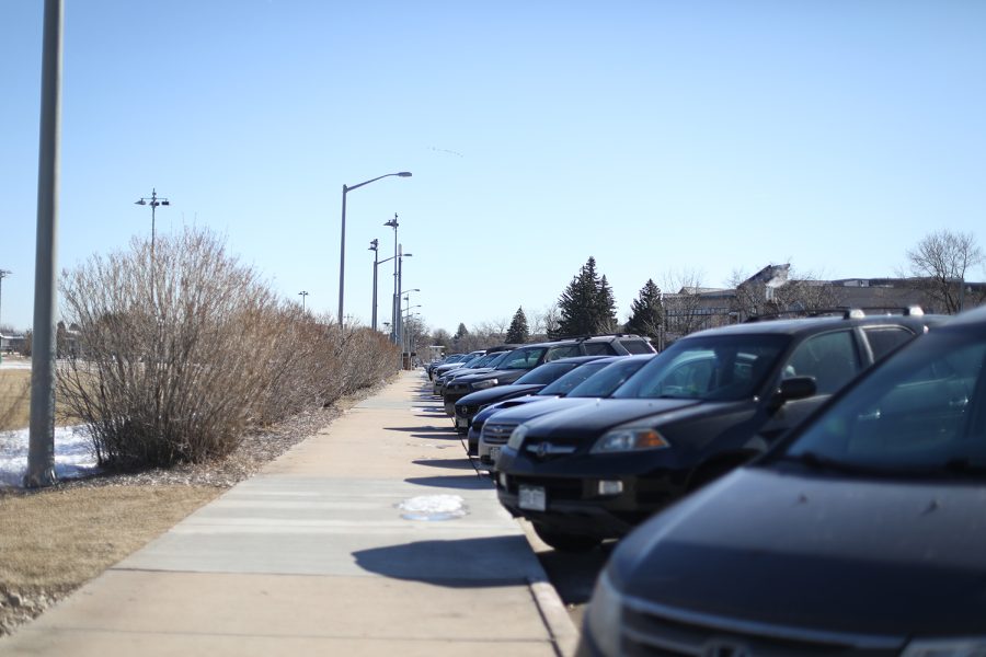Cars are parked along a sidewalk on a sunny day