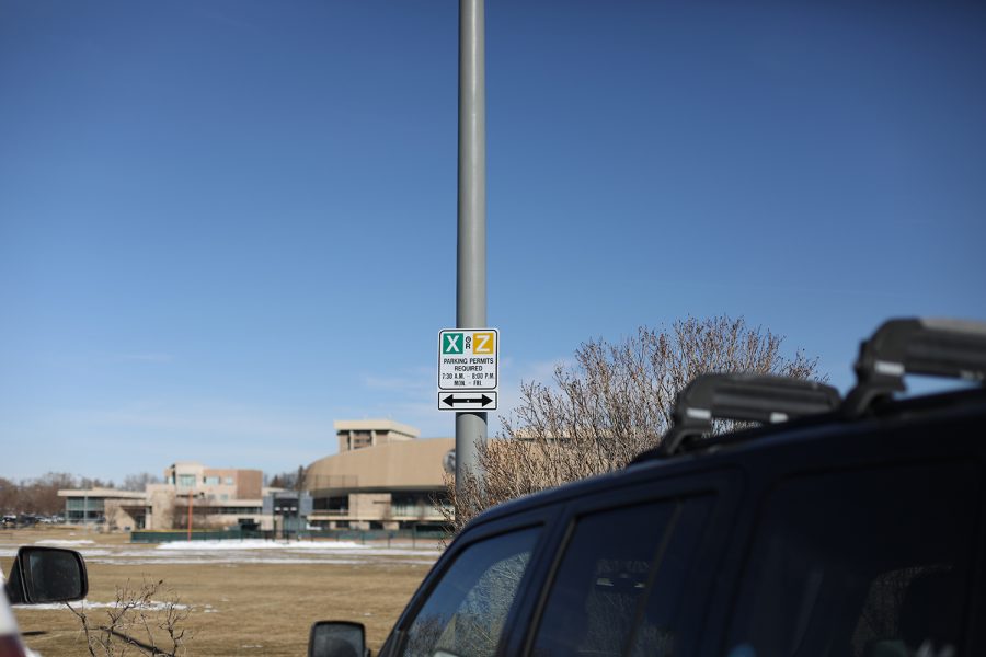 A street sign that says X or Z parking permits required 7:30 a.m. to 8 p.m. Monday through Friday sits on a light pole