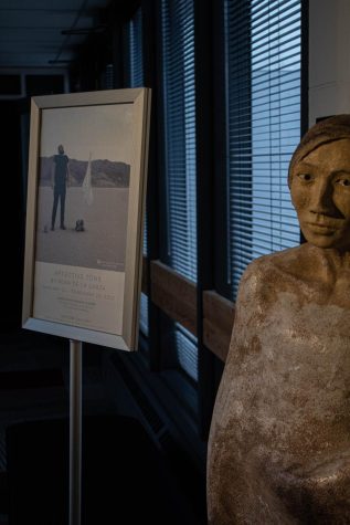 A statue of a woman sits beside a promotional sign about the Affective Tone exhibit in the Hatton Gallery. Behind this are windows with closed blinds.