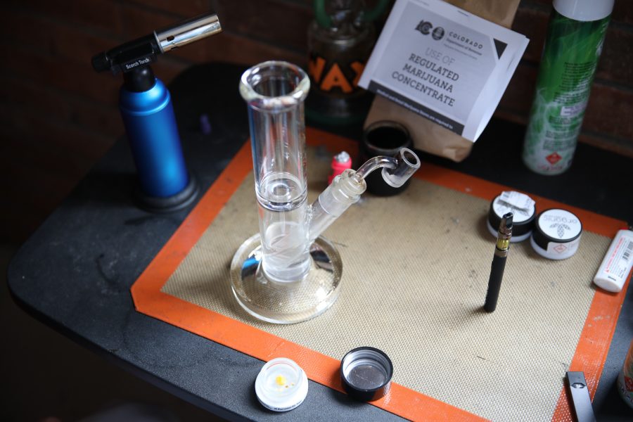 A photo illustration of a smoking set up that features cartons of wax, a Juul, a dab pen and various other smoking accessories.