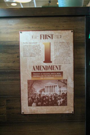 A poster depicting the First Amendment hangs across from the register.