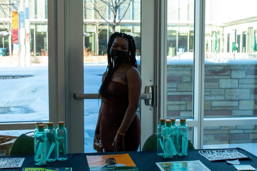 Josie Brown stands near a table with water bottles to welcome community members to the Black History Month Kick-off event