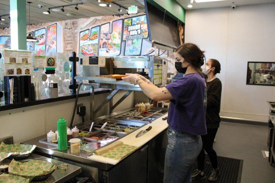 A Cheba Hut employee takes a sandwich out of the toaster.