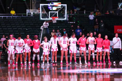 The Womens Basketball team stands for the National Anthem.
