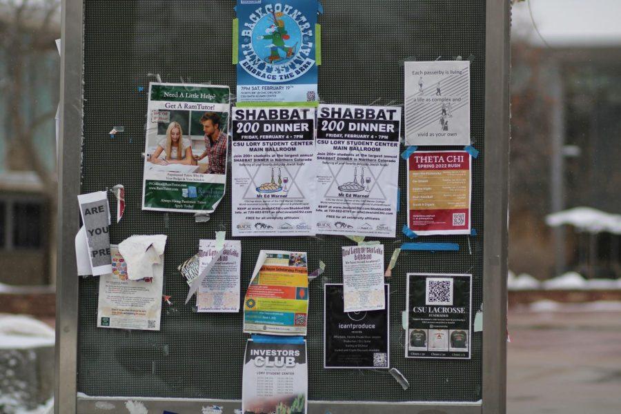 Posters and flyers hang from an outdoor messenger board on the plaza outside of the Lory Student Center.