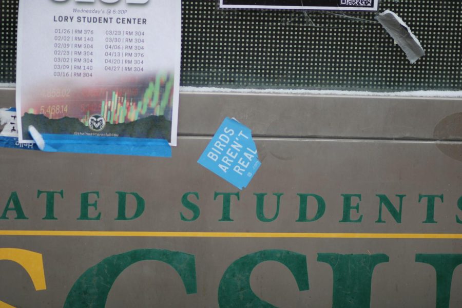 A "Birds Aren't Real" sticker adorns an outdoor messaging board on the plaza outside of the Lory Student Center.