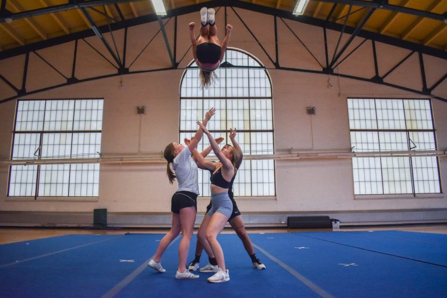 Colorado State University cheerleaders catching a flyer in the midst of a stunt during one of the final practices for seniors as they prepare to graduate in the spring.