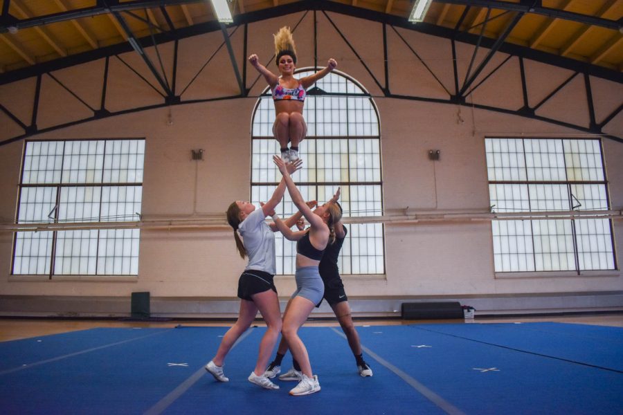 Colorado State University cheerleaders catching a flyer in the midst of a stunt during one of the final practices for seniors as they prepare to graduate in the spring.
