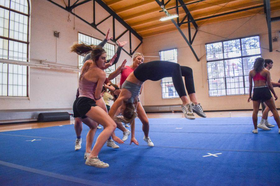 Colorado State University cheerleaders beginning a stunt during one of the final practices for seniors as they prepare to graduate in the spring.