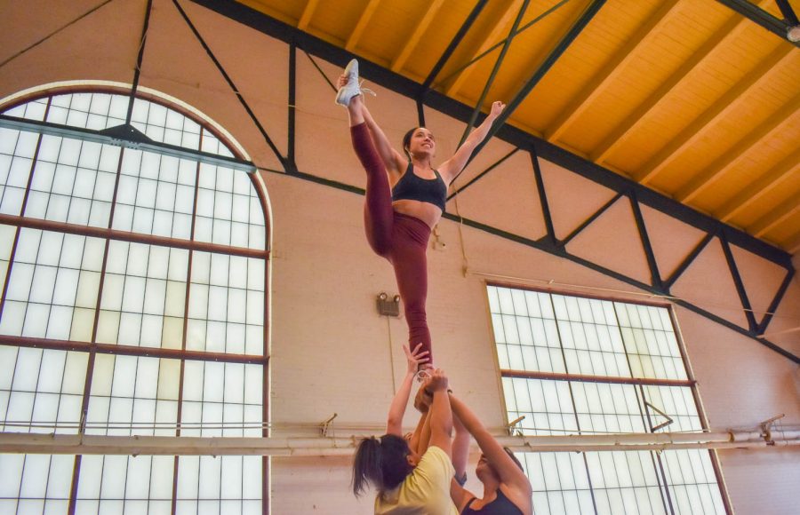 Colorado State University cheerleaders holding a flyer (Bianca Gonzalez) in a stunt during one of the final practices for seniors as they prepare to graduate in the spring.