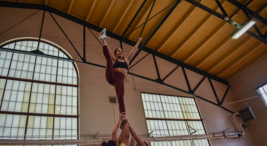 Colorado State University cheerleaders holding a flyer (Bianca Gonzalez) in a stunt during one of the final practices for seniors as they prepare to graduate in the spring.