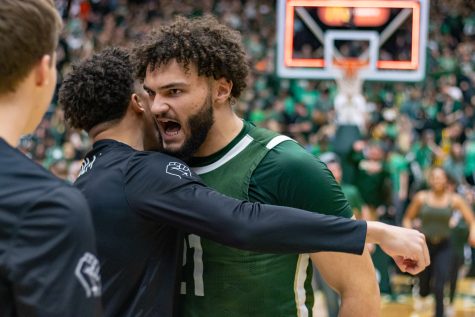 Colorado State Forward David Roddy (21) celebrates with a teammate as fans storm the court after CSU defeats Boise State University.