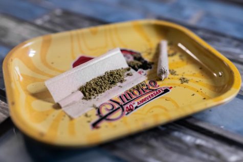 A joint sits filled with ground cannabis flower, waiting to be rolled and sealed