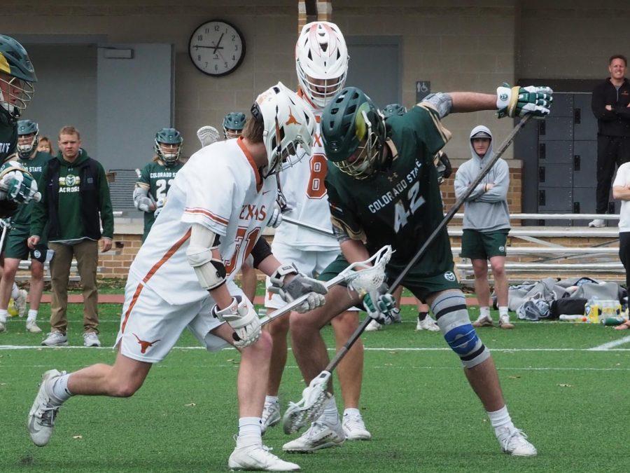 Colorado State Defender Shane O'Brien scoops up a loose ball against Texas attacker John Burton in their game against the University of Texas men's lacrosse team March 13, 2022.