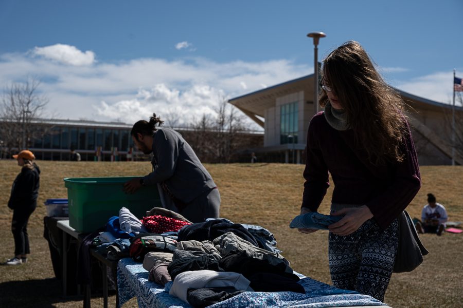 Esme Holden (Right), volunteer for ClotheThePeople, lays out their table with free clothing for those who need it at K-Colorado State University’s FoolsFest Apr 1. “ClotheThePeople has been working for Blast N Scrap for almost a year now, we provide food, clothes, hygiene products and survival gear to the homeless community,” Holden stated, “Its really challenging, everyone has different capacity levels and its all-volunteer work. We accept any donations, anything you would want if you were homeless and we distribute that every Sunday at the Mennonite’s church at 2:15pm in Library Park and the Murphy Center every Sunday at 3:15pm.”