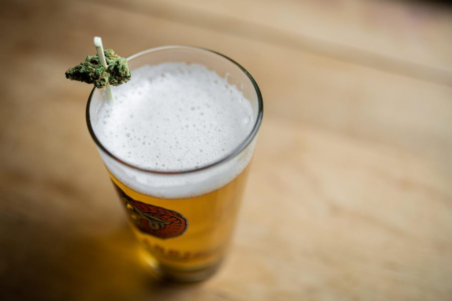 A cannabis flower bud rests on the rim of a glass of New Belgium Brewings Old Aggie lager