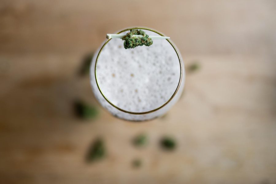 A glass of New Belgium Brewings Old Aggie lager sits surrounded by cannabis flower buds
